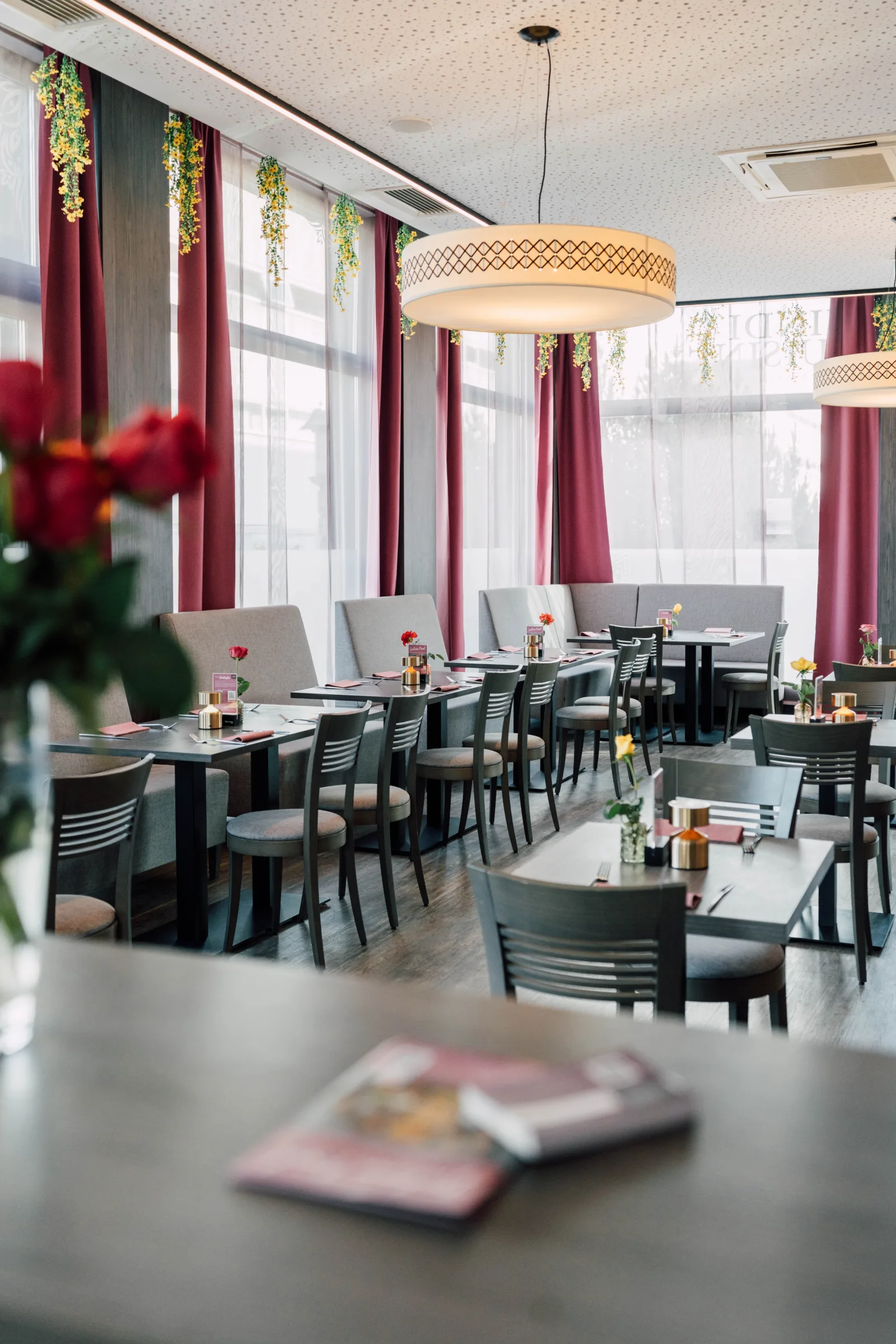 Before: Indisches Restaurant in Wien — leerer Speisesaal mit roten Vorhängen und gelben Blumengirlanden