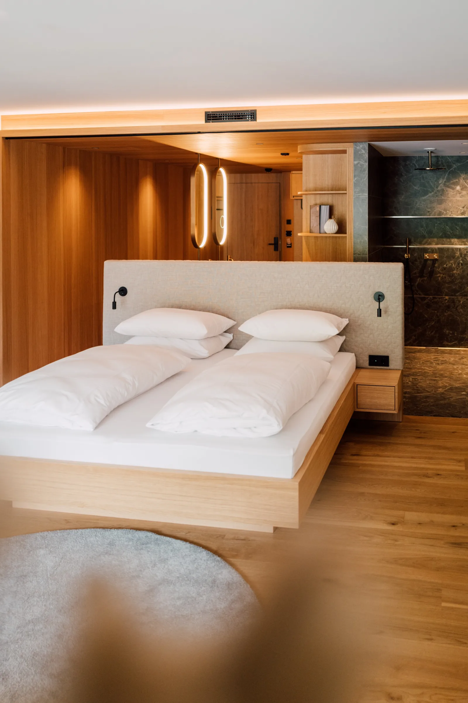 Before: Hotelsuite mit Eichen-Wandverkleidung, ovoiden Pendant-Lichtern und Marmor-Bad rechts